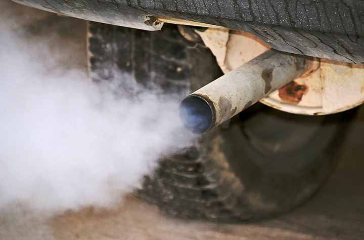auton hieman ruosteinen pakoputki ja sankkaa pakokaasua