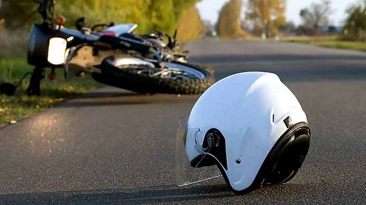 kypärä ja kaatunut mopo tiellä