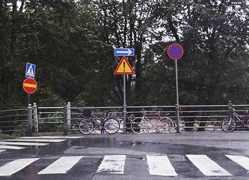 erinäisiä liikennemerkkejä kaupunkialueella ja pyöriä jalkakäytävällä