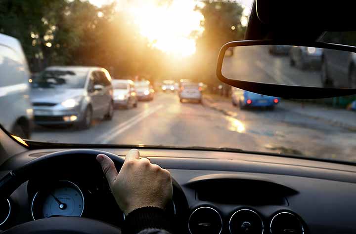 vilkasta kaupunkiliikennettä auringon laskiessa ja häikäistessä